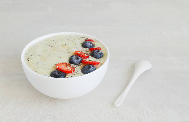 A delicious bowl of banana and kiwi smoothie, decorated with fresh berries and chia seeds. Bright fruits for detox breakfast. Concept of Breakfast bowl or wholesome meal. Minimalism style.