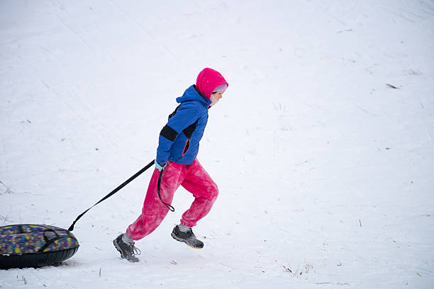 Family on the winter vacation sledding downhill