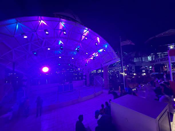 Miami, Florida, United States of America - January 10, 2026: Bayside Marketplace at night draws tourists to waterfront concerts and lively outdoor entertainment, bathed in purple and blue neon lighting with crowds enjoying music and city vibes