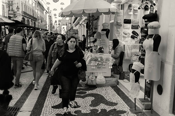 Lisbon, Portugal - November 2, 2024: A seamstress waits for clients outside a shop at the Rua Augusta street in Lisbon downtown.