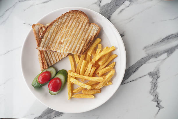A fresh sandwich and golden fries presented with vegetables for garnish.