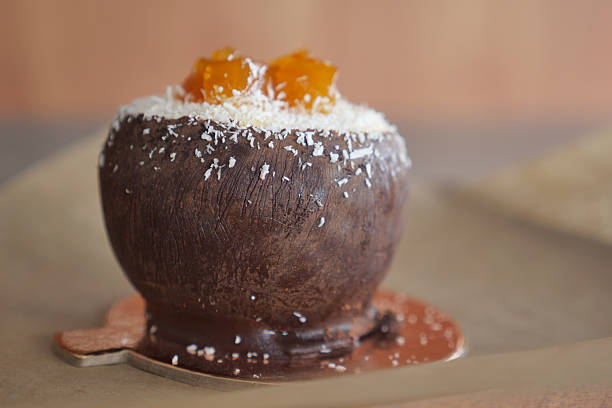 A unique dessert in a coconut bowl topped with sweet fruit and coconut flakes.