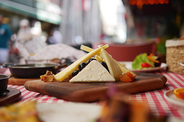 A wooden board showcases various cheeses with colorful toppings.