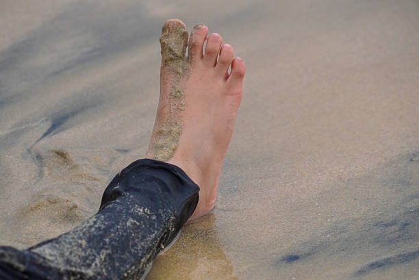 Feet standing on beach sand that has just been touched by water