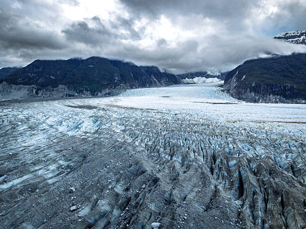 Wide-angle view of the glacier flowing through a deep valley, with fractured ice patterns creating strong visual lines across the frame. The image conveys movement, scale, and the wild character of southern Chile’s glacial landscapes.