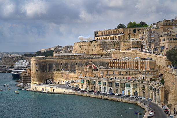 Firing of the cannon saluting battery at the Upper Barrakka Gardens in Valletta, Malta. Taken at noon from an alternative viewpoint looking over towards The Grand Harbour and Fort Lascaris.