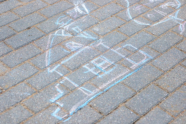 A detailed drawing of a skeleton is beautifully written in white chalk on a textured brick sidewalk, showcasing artistic creativity