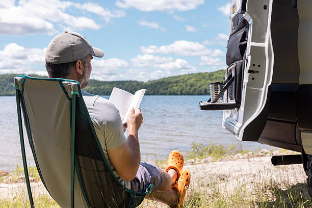 Man Relaxing Close to a Lake With Camper van During Summer