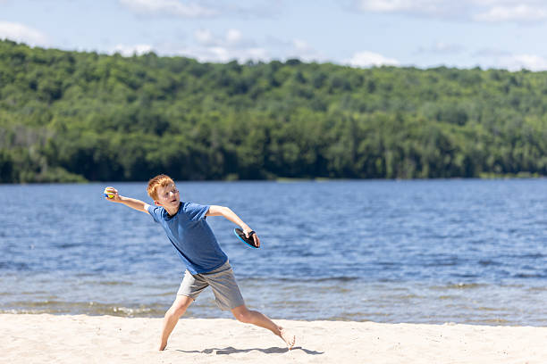 Boy playing throwing stones into a lake in winter