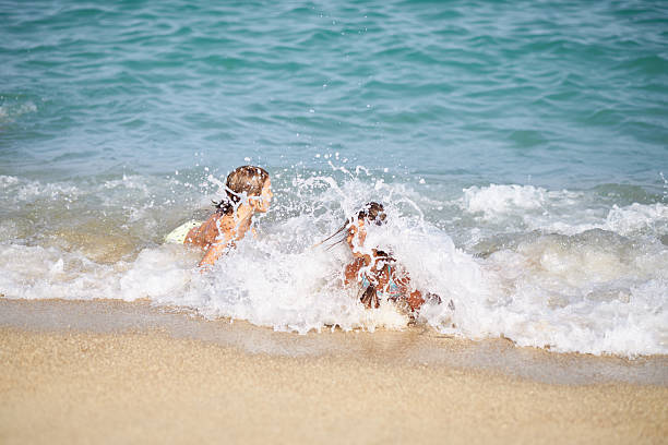 Young caucasian boy and girl jumping into waves. They are swimming and diving in clear turquoise colored sea.