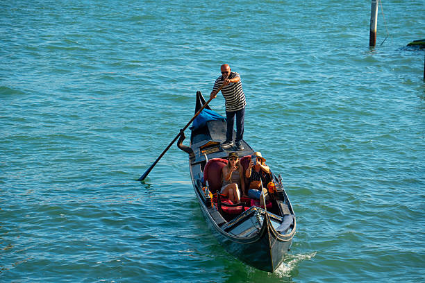 VENICE, ITALY - SEPTEMBER 26, 2021: A gondolier steers his boat into moorage just as raindrops start to fall on Venice.