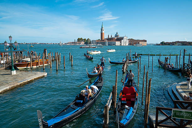 Venice, Italy - September 23, 2023: Tourists are enjoying a traditional gondola ride across the busy waters of the venice lagoon, experiencing italian culture and viewing the iconic san giorgio maggiore island from the water