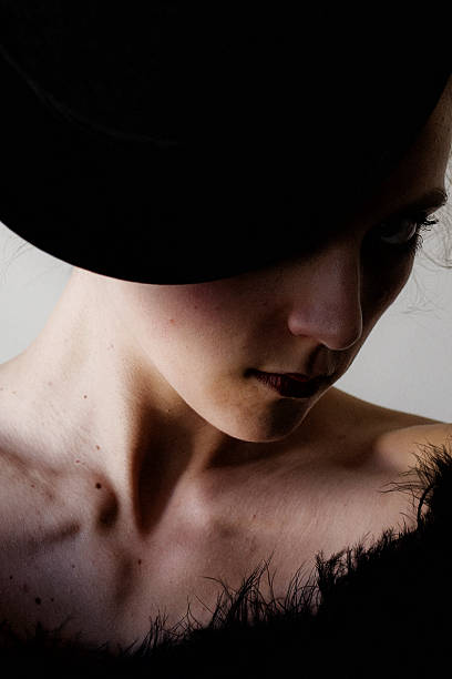 Playful young woman in funny hat with rabbit, studio shot