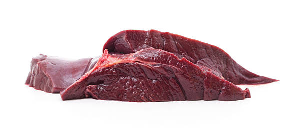 Close-up shot of hands tying raw rolled veal slices in plate at table while preparing meal on table at home