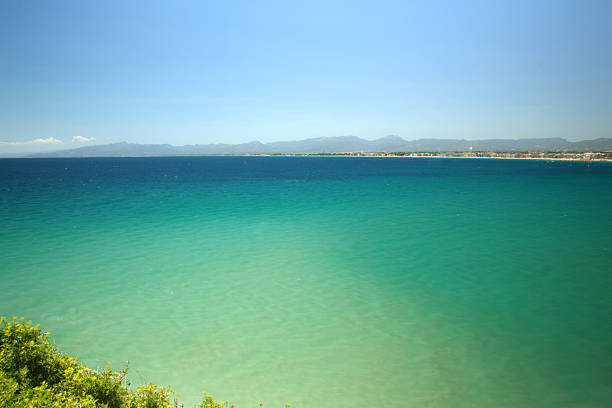 A serene coastal landscape with clear blue and green waters under a bright sky.