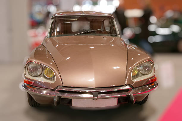 A vintage car with gold accents and a large headlight. The car is parked in a museum