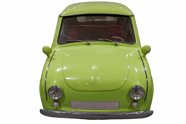 The image shows a green car parked in a museum or exhibition setting. The car has round headlights and a simple design. There are no other vehicles or people around it.