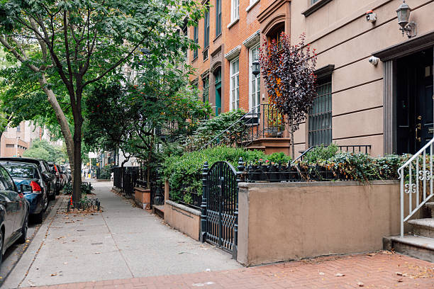 Sidewalk view of an urban residential area with trees and classic buildings.