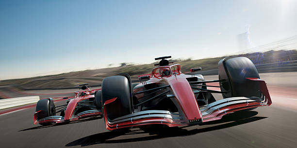 A close up view of two generic red racing cars moving at high speed on a generic racetrack under avlear blue afternoon sky.