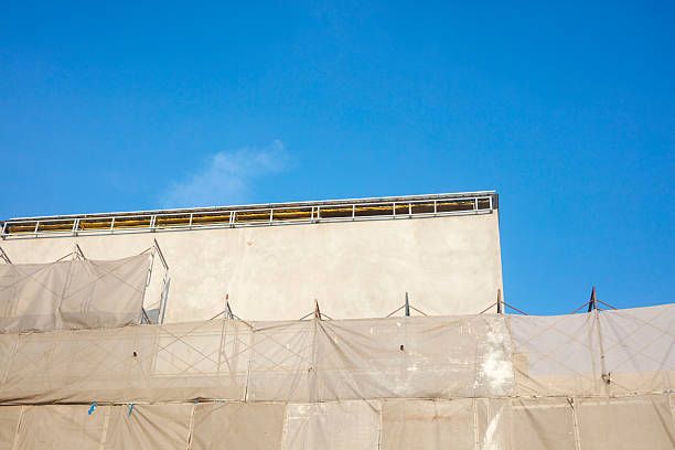 Blank white long banner with place for mockup fixed on building facade wall with scaffold during reconstruction outside