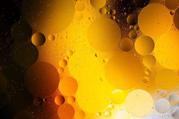 Close up macro image depicting droplets of oil in water on a multi colored background. The oil forms interesting circles and spheres in the water, and colorful background produces an abstract effect.