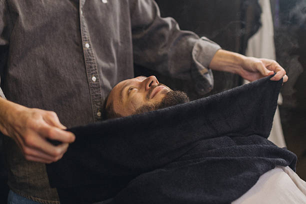 Relaxed male client lying in barber chair during classic shaving procedure. Professional barbershop service, beard grooming, comfort and men self care lifestyle concept