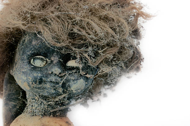 Photo of an old broken porcelain doll's head with empty eye sockets. It lies on a rusty metal base.