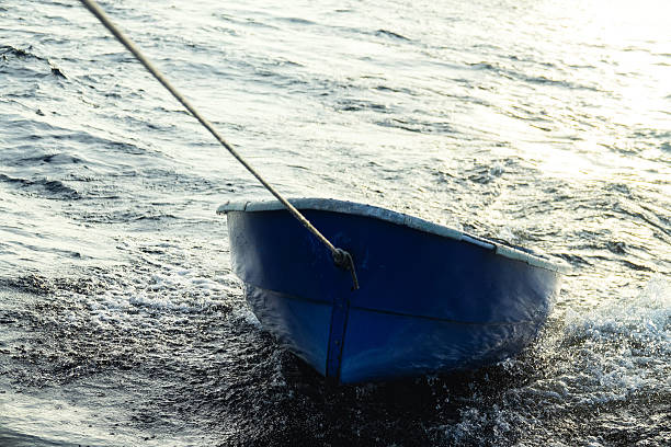 boat is tethered behind fishing schooner, on trailers, under tow