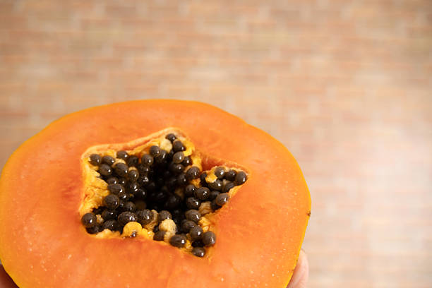 Papaya cut in half, revealing the star-shaped core with the seeds inside.