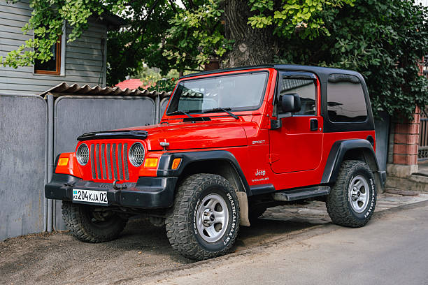 Almaty, Kazakhstan - July 30, 2025: A red Jeep Wrangler parked near the road. An American SUV