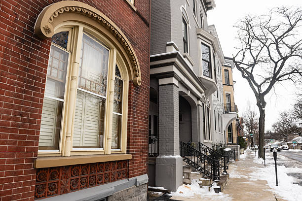 This is a photograph of a large arched window in a Late Victorian Brick Row House among a block of historic buildings connected with a sidewalk on a winter day in Easton, Pennsylvania.