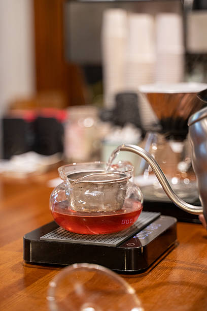 Pouring Hot Water into a Glass Teapot with Herbal Tea