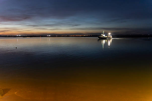 Guadiana river with a fishing boat Sunset from the The Lighthouse of Isla Cristina   Faro del Cantil Building, a construction on Punta del Caimán that houses homes and commercial premises, including a cafe with spectacular views of the marshes, being a key point on the Huelva coast to enjoy sunsets Andalusia Spain