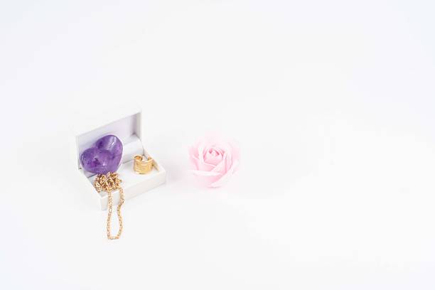 purple heart and jewelry box as a Valentine's gift and a rose with a white background
