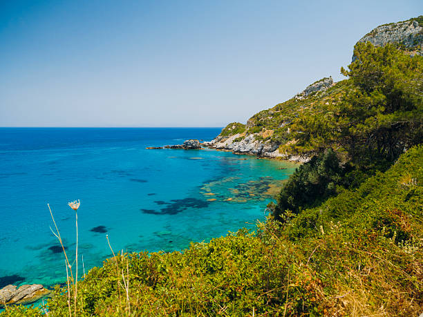 Potami Beach on Samos Island featuring clear turquoise waters, a pebble shoreline, and dramatic natural scenery along the Aegean Sea, offering a tranquil coastal atmosphere and a popular destination for summer travel in Greece.
