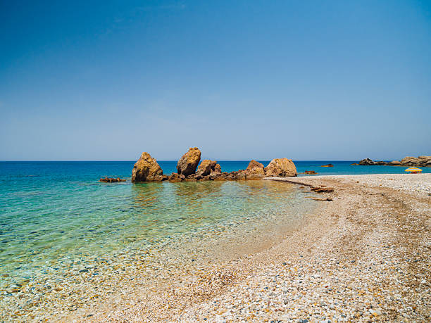 Potami Beach on Samos Island featuring clear turquoise waters, a pebble shoreline, and dramatic natural scenery along the Aegean Sea, offering a tranquil coastal atmosphere and a popular destination for summer travel in Greece.