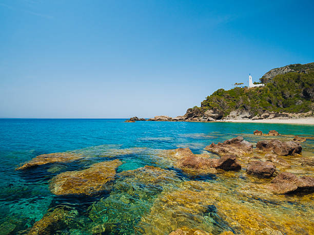 Potami Beach on Samos Island featuring clear turquoise waters, a pebble shoreline, and dramatic natural scenery along the Aegean Sea, offering a tranquil coastal atmosphere and a popular destination for summer travel in Greece.