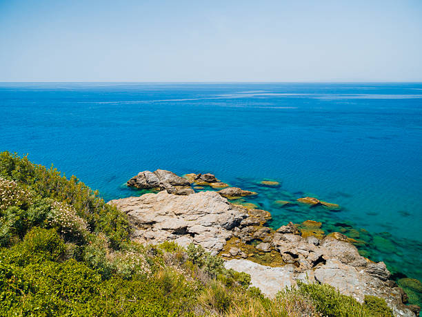 Potami Beach on Samos Island featuring clear turquoise waters, a pebble shoreline, and dramatic natural scenery along the Aegean Sea, offering a tranquil coastal atmosphere and a popular destination for summer travel in Greece.