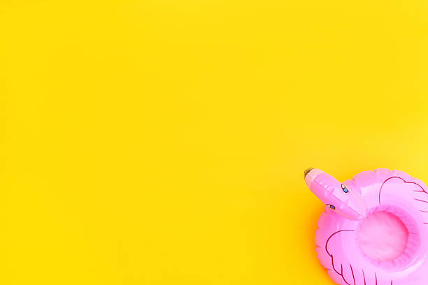 Summer beach composition. Simply minimal design with pink Inflatable flamingo isolated on yellow background. Pool float party, trendy celebrity fashion concept. Flat lay top view copy space