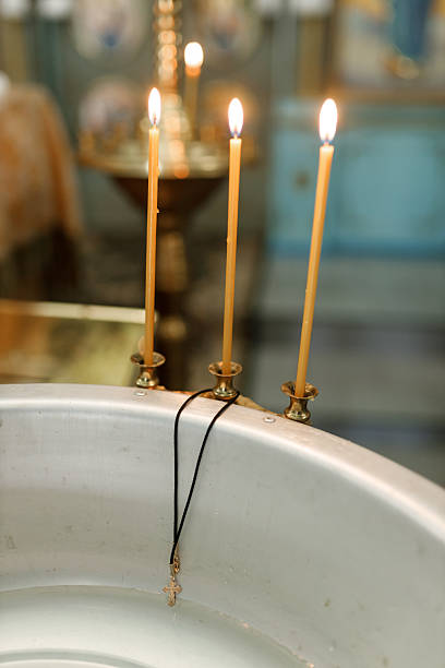 Golden cross hanging on baptismal font between three candles
