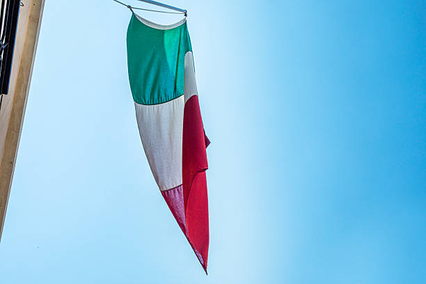 Italian flag against a blue sky, view from below. Political strategy