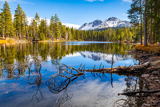 Snow covered Lassen Peak reflects in calm Manzanita Lake at Lassen Volcanic National Park California