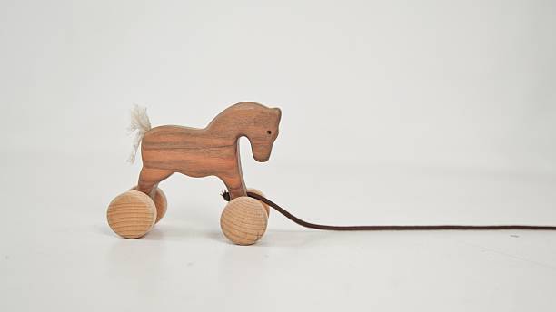 A charming, handcrafted wooden horse toy on wheels, complete with a trailing string, presented against a minimalist white backdrop