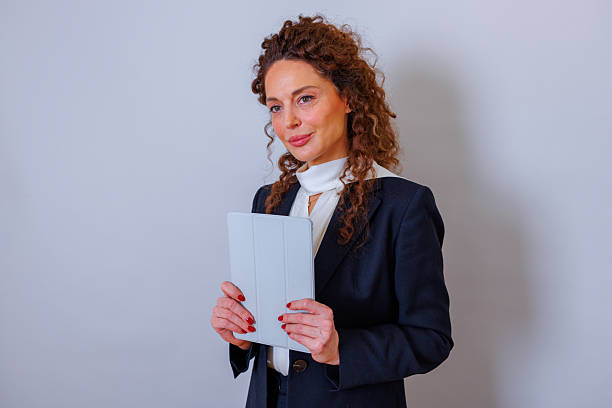 Experienced businesswoman holding a digital tablet, embodying innovation and technology. She is a confident professional