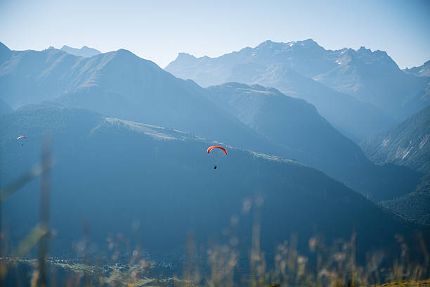 Alone paraglider soars through a partly cloudy sky with vibrant blue tones. A perfect image of freedom, extreme sports, and adventure in nature.