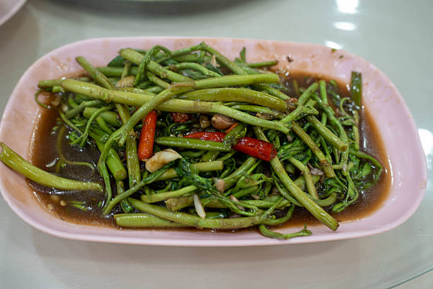 A close-up of stir-fried water spinach, showcasing its fresh texture, aromatic seasoning, and the essence of traditional Thai home cooking.