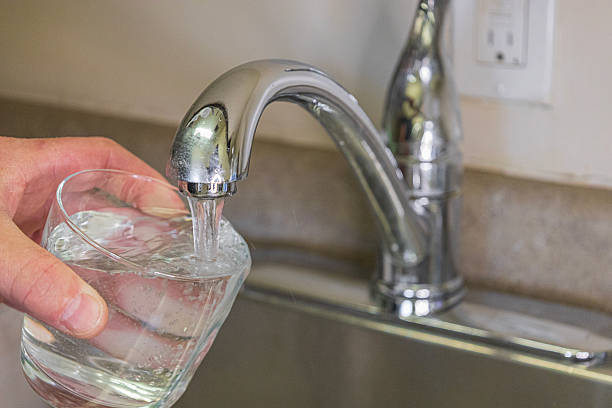 Bathroom faucet, running water, white enamel sink, bathtub.
