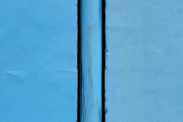 Close-up on a blue metal water pipe in a blue wall.