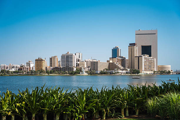 Cityscape of Jeddah featuring modern skyscrapers and waterfront view with lush greenery in the foreground under a clear blue sky, highlighting urban development and natural elements in this vibrant city.