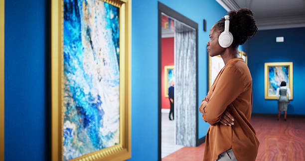 Black Woman Observing Artwork In Museum Gallery With Audio Guide